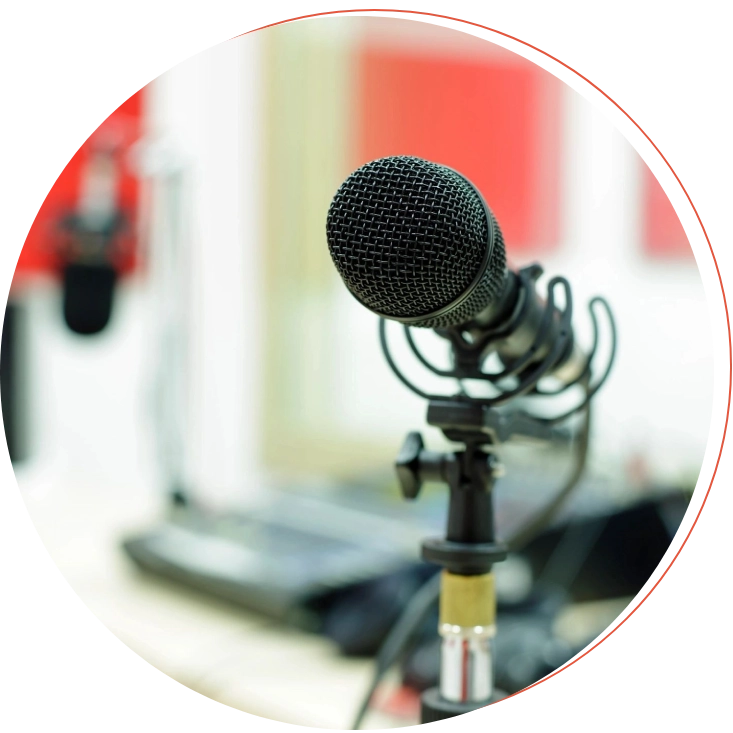 Close-up of a black microphone in a recording studio with blurred background equipment.